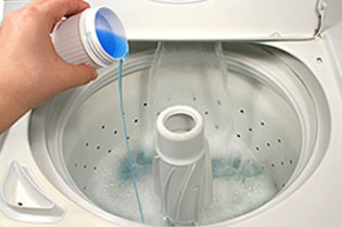 A person pours laundry detergent into a washing machine.