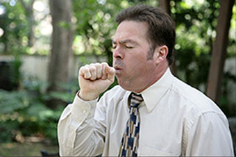 A man coughs into his hand.