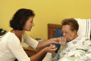 Daughter helping Mother drink a glass of water