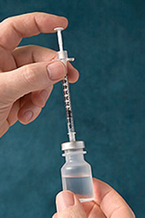 a person prepares an injection syringe