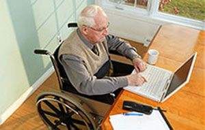 A man in a wheelchair uses a laptop