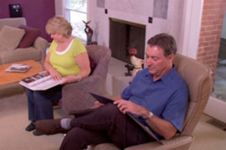 man and woman sitting in chairs reading